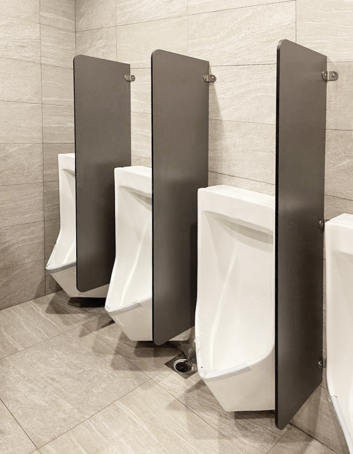 Grey phenolic urinal partition in a commercial washroom